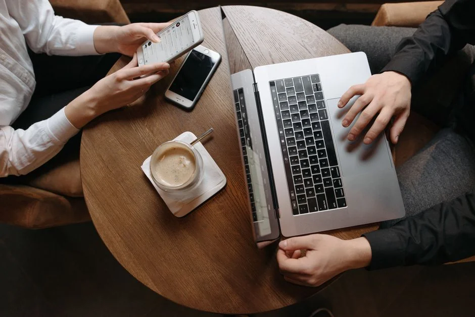 Personne utilisant un smartphone pour analyser le marché boursier dans un bureau à domicile.