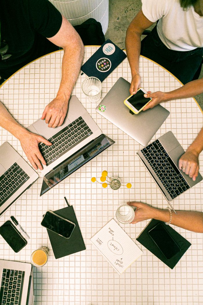 Vue du dessus d’une équipe collaborant avec des ordinateurs portables, des téléphones et des notes dans un bureau moderne.