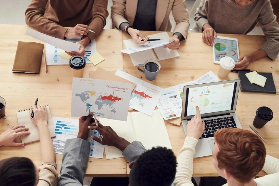 Une équipe variée travaille ensemble sur des stratégies de marketing digital autour d’une table, avec des ordinateurs portables et des tablettes.